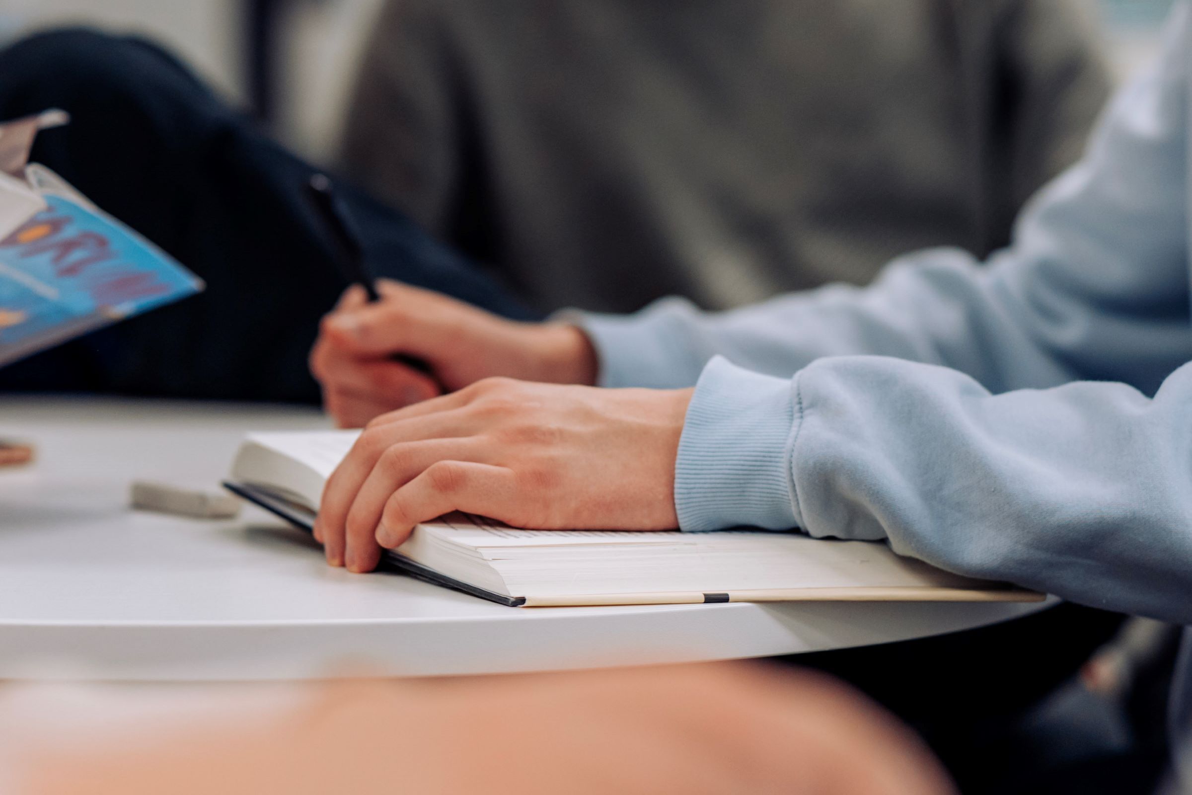 Kuva on koristekuva. Kuvassa kädet kirjalla.