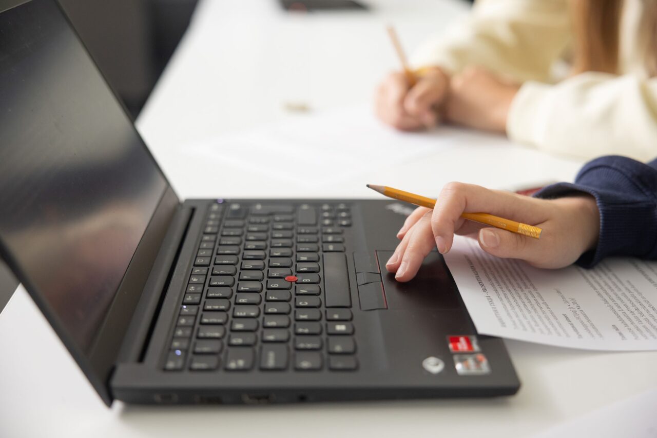 Kuva on koristekuva. Tietokone, kynä ja moniste kuvassa.